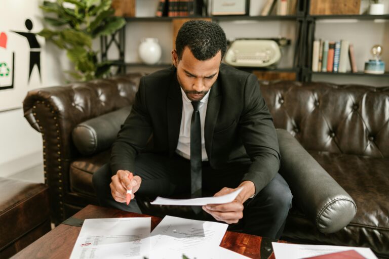 How Much Does SEO Cost in Nigeria? A businessman in a suit attentively reviews paperwork on a brown leather sofa.
